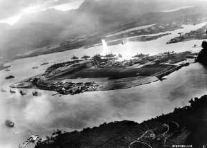 Angriff auf Pearl Harbor, auf die im Hafen liegenden Schiffe. In der Mitte eine Explosion nach einem Torpedotreffer auf die USS Oklahoma. See page for author [Public domain], via Wikimedia Commons