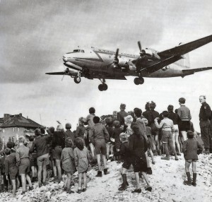 Berliner beobachten die Landung eines Rosinenbombers auf dem Flughafen Tempelhof (1948). By USAF [Public domain], via Wikimedia Commons