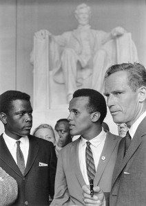 Harry Belafonte (Mitte) auf dem Marsch für Bürgerrechte 1963 in Washington D.C. mit Sidney Poitier (l.) und Charlton Heston (r.), By U.S. Information Agency. Press and Publications Service. (ca. 1953 - ca. 1978) [Public domain], via Wikimedia Commons