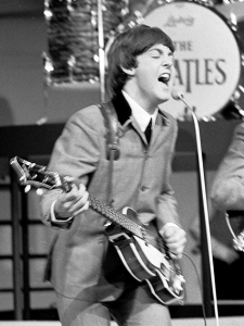 Paul McCartney bei einem Auftritt der Beatles, 1964, By BeatlesVara1964.png: http://beeldengeluidwiki.nl/index.php/Gebruiker:Bvspallderivative work: Guitarpop (BeatlesVara1964.png) [CC BY-SA 3.0 nl], via Wikimedia Commons