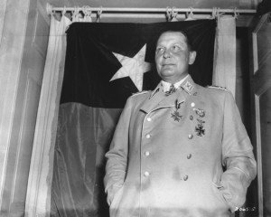 Hermann Göring kurz nach seiner Festnahme am 9. Mai 1945 vor einer texanischen Flagge. Orden und Ehrenzeichen hatte man ihm für diese Aufnahme zurückgegeben.  Gemeinfrei via Wikimedia Commons 